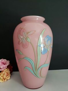 a pink vase with flowers painted on it