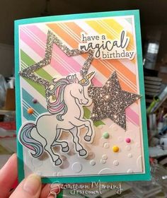 someone holding up a birthday card with a unicorn on the front and stars on the back