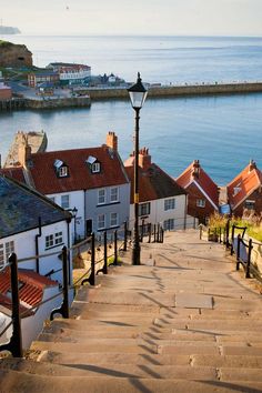 stairs lead down to the beach with houses on either side and water in the background