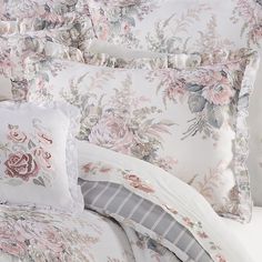 the comforter is made up with pink and white flowers on it, along with matching pillows