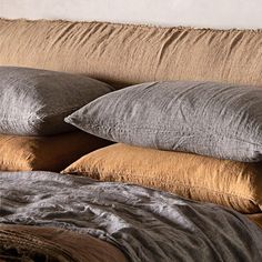 pillows and blankets are stacked on top of each other in front of a white wall