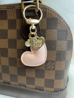 a brown and pink purse with a heart shaped keychain hanging from it's side