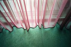 a pink curtain is hanging in front of a window