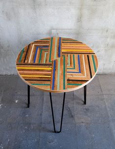 a wooden table with multicolored lines on it and black hairpin legs in front of a white wall