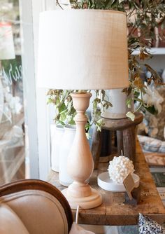 a lamp sitting on top of a wooden table next to a vase filled with flowers