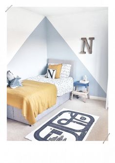 a bed room with a neatly made bed next to a wall mounted letter n on the wall