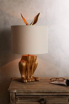 a golden cat lamp sitting on top of a table next to a pair of glasses