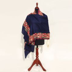 Presenting our exquisitely crafted navy blue based High-Quality Embroidered Kashmiri Pashmina Wool Shawl, a masterpiece that exudes sophistication and warmth. Layered with intricate floral multicolored Aari embroidery, this shawl is a true work of art, designed to enhance your winter style. This medium-length piece, fully embroidered by machine, complements both neutral and colored outfits effortlessly, making it the perfect accessory for the winter season. Ideal for formal occasions, it adds a vibrant touch to your ensembles, elevating your overall look. With its versatility, this medium-length shawl seamlessly pairs with both Eastern and Western outfits, adding a touch of elegance wherever you go. Crafted with care, each piece is unique, available in limited quantity and sizing, ensuring Embroidered Scarves For Eid, Pashmina Shawl With Floral Embroidery, Elegant Embroidered Blue Shawl, Blue Pashmina Shawl For Winter, Traditional Blue Pashmina Scarves, Blue Embroidered Pashmina Shawl, Traditional Blue Shawl With Embroidered Border, Blue Pashmina Shawl With Traditional Drape, Blue Traditional Pashmina Shawl