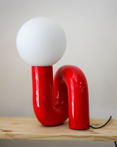 a red and white lamp sitting on top of a wooden table