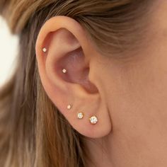 a close up of a person's ear with three small diamond studs on it