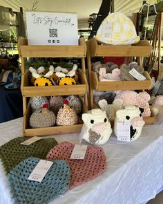 there are many knitted items on display at this market stall, including hats and mittens