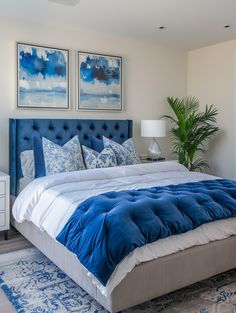 a blue and white bed in a bedroom with two paintings on the wall above it