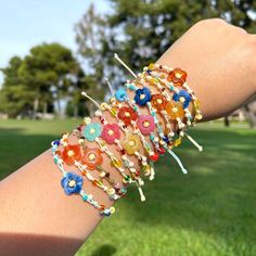 a woman's arm with bracelets made out of beads and flowers on it