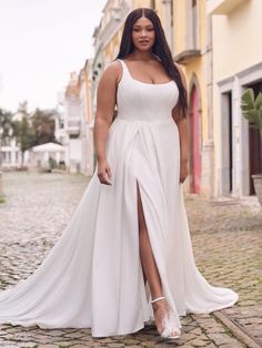 a woman in a white dress standing on a cobblestone street