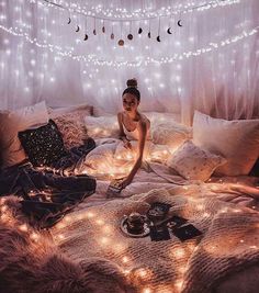 a woman sitting on top of a bed covered in lights