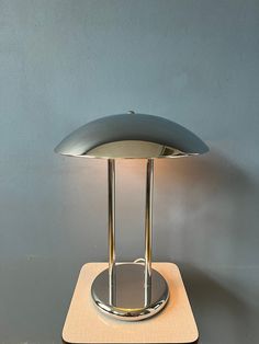 a table lamp sitting on top of a wooden stand next to a gray wall and floor