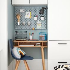 a desk and chair in a room with blue walls, white cupboards and black polka dot wallpaper