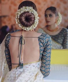 the back of a woman's dress with flowers in her hair