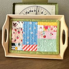 a wooden tray with patchwork quilts and a ruler in it on top of a table