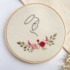 a close up of a embroidery on a white surface with flowers and leaves around it