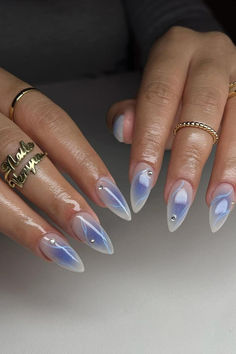 Gorgeous Milky White Stiletto Nails with a Purple Aura and Blue Marble Art, adorned with Sparkling Crystal Accents, creating a dreamy and ethereal look. // Photo Credit: Instagram @v.nailedit_ April Almond Nails, Eyeshadow Nails, Aura Nails, Blush Nails, Pretty Gel Nails, Almond Nails Designs, Blue Nail, Thanksgiving Nails