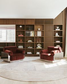 a living room with two red chairs and a book shelf filled with books on it