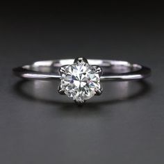 a white gold engagement ring with a round cut diamond in the center, on a black background