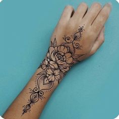 a woman's hand with a flower tattoo on the wrist and an intricate design