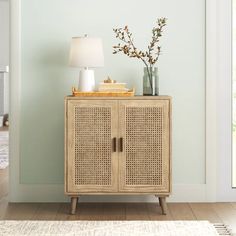 a wooden cabinet with two doors and a lamp on top of it next to a rug