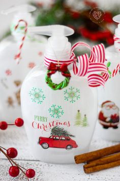 three christmas themed bottles with cinnamon sticks in front of them and some decorations on the table