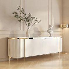 a white and gold sideboard with vases on it in an elegant living room