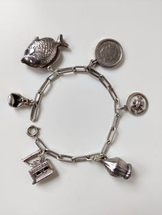 Prachtige vintage design armband in zeer goede staat met unieke bedeltjes. Staat prachtig om de pols met en zet een uniek tijdsbeeld neer. Goed werkende sluiting met een vaste veiligheidsketting  Bedels: - Vis - Boxhandschoen - Strijkijzer - Wijnfles - Schorpioen - Wilhelmina Kwartje / 25 cent (gulden) Gewicht volledige armband: 27.67 gram Lengte armband: 18,8 cm Zorgvuldige verpakking en verzekerde verzending Antique Style Bracelets With Dangling Charms As Gift, Antique Bracelets With Dangling Charms As Gift, Vintage Metal Jewelry For Collectors, Antique Bracelets With Dangling Charms For Gift, Antique Bracelets With Vintage Charm As Gift, Antique Charm Bracelet Jewelry, Antique Charms Bracelet Jewelry, Antique Metal Bracelet With Charms, Handmade Vintage Metal Charm Bracelet