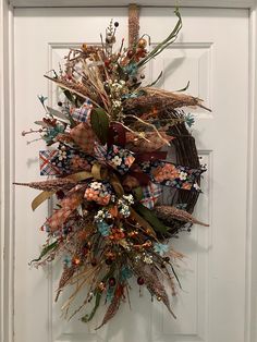 a wreath on the front door is decorated with dried flowers and leaves, along with an orange ribbon