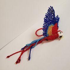 the beaded bird is red, white and blue with long tail feathers on it's head