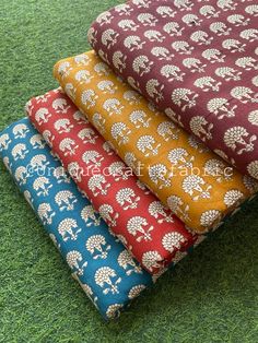 four pieces of fabric with elephants and trees on them in different colors, sitting on the grass