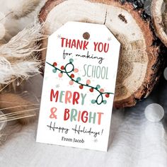 a thank you for making school merry and bright tag on a piece of wood next to some feathers