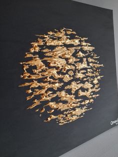 an abstract painting with gold paint on a black background is featured in this image, it appears to be made out of wood