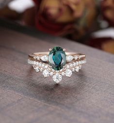 a green and white diamond ring sitting on top of a wooden table next to a woman's face