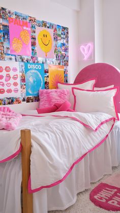 a pink and white bedroom with pictures on the wall above the bed, along with pillows