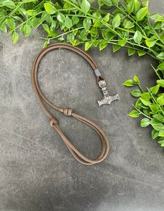 a leash with a cross on it next to some green plants and leaves in the background