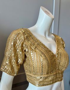 A golden color blouse Product details Fabric - silk blend Embroidery - sequins Bust size 36" Waist 30" sleeve length 10" Can be tailored to fit 38" For extra charges Golden Heavy Blouse, Blouse Designs Golden Color, Festive V-neck Evening Blouse, Fitted V-neck Sequin Blouse, Fitted Sequined V-neck Blouse, Fitted V-neck Top With Mirror Work, Reception Blouse Piece With Mirror Work V-neck, Reception V-neck Blouse Piece With Mirror Work, Gold V-neck Blouse For Wedding