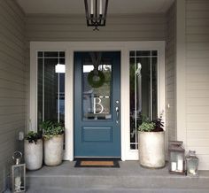 a blue front door with two planters on the step and a lantern hanging above it