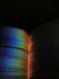 an open book sitting on top of a table next to a light reflecting from it