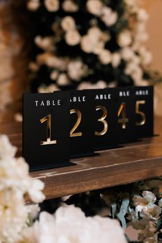 the table numbers are black and gold with white flowers in the backgroung