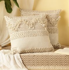 two pillows on a bed with a plant in the corner and a book beside them