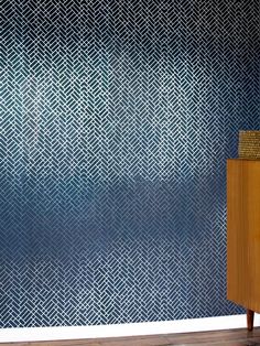 a blue and white wall with a wooden cabinet next to it on a hard wood floor