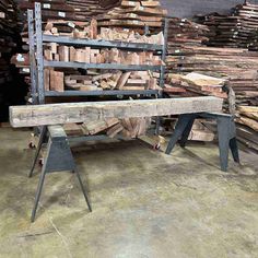 a bench made out of wood and metal stands in front of stacks of lumbers