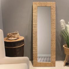 a mirror sitting on top of a floor next to a plant