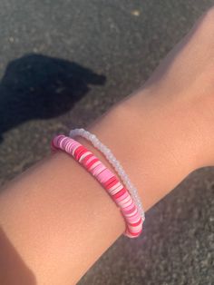 a close up of a person's arm wearing a bracelet with pink and white beads