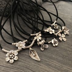 Unique one of a kind silver flower charms choker. 10 different necklaces, made with a long black leather cord and 10 unique silver flower pendants with silver beads. This necklaces can be adjusted to chokers or can be long necklaces like you can see in the picture. Perfect stacking necklaces that will rock your outfit and will be easy to match other accessories. You can see in 2 of the pictures that each flower choker has a number, that way you know which one are choosing. A unique addition to y Festival Jewelry With Flower Charm, Adjustable Flower Pendant Necklaces With Cord, Adjustable Flower Pendant Necklaces With Adjustable Cord, Necklaces With Adjustable Cord And Flower Pendant, Bohemian Silver Choker With Adjustable Cord, Silver Bohemian Choker With Adjustable Cord, Adjustable Flower Charm Pendant Necklace, Adjustable Silver Charm Necklace For Festivals, Silver Adjustable Cord Necklace For Festivals